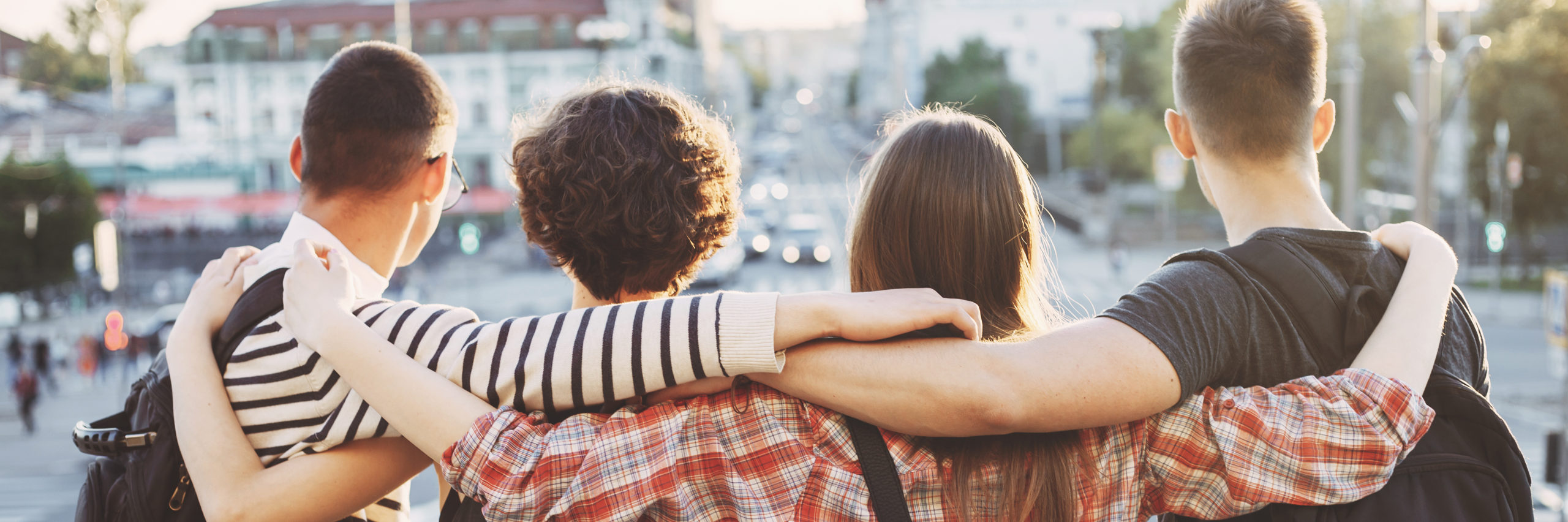 Friendship, traveling, sightseeing, adventure, togetherness, student exchange program. Young people with backpacks standing close hugging at city background - Image