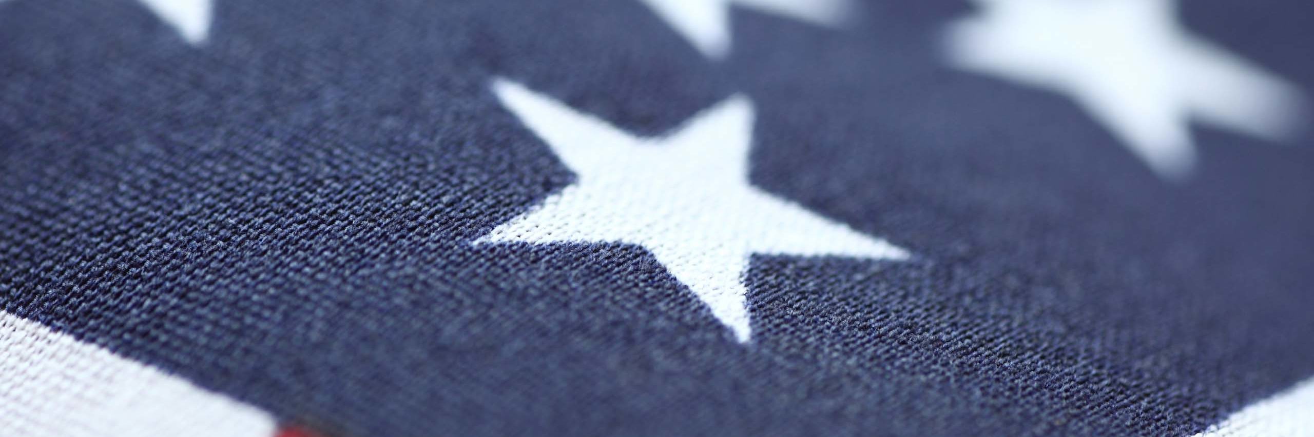 A close-up view of the American flag, showing a white star against a dark blue background, and a small strip of red.