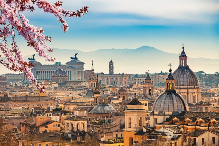 A view of Rome showing rooftops and mountains in the background.