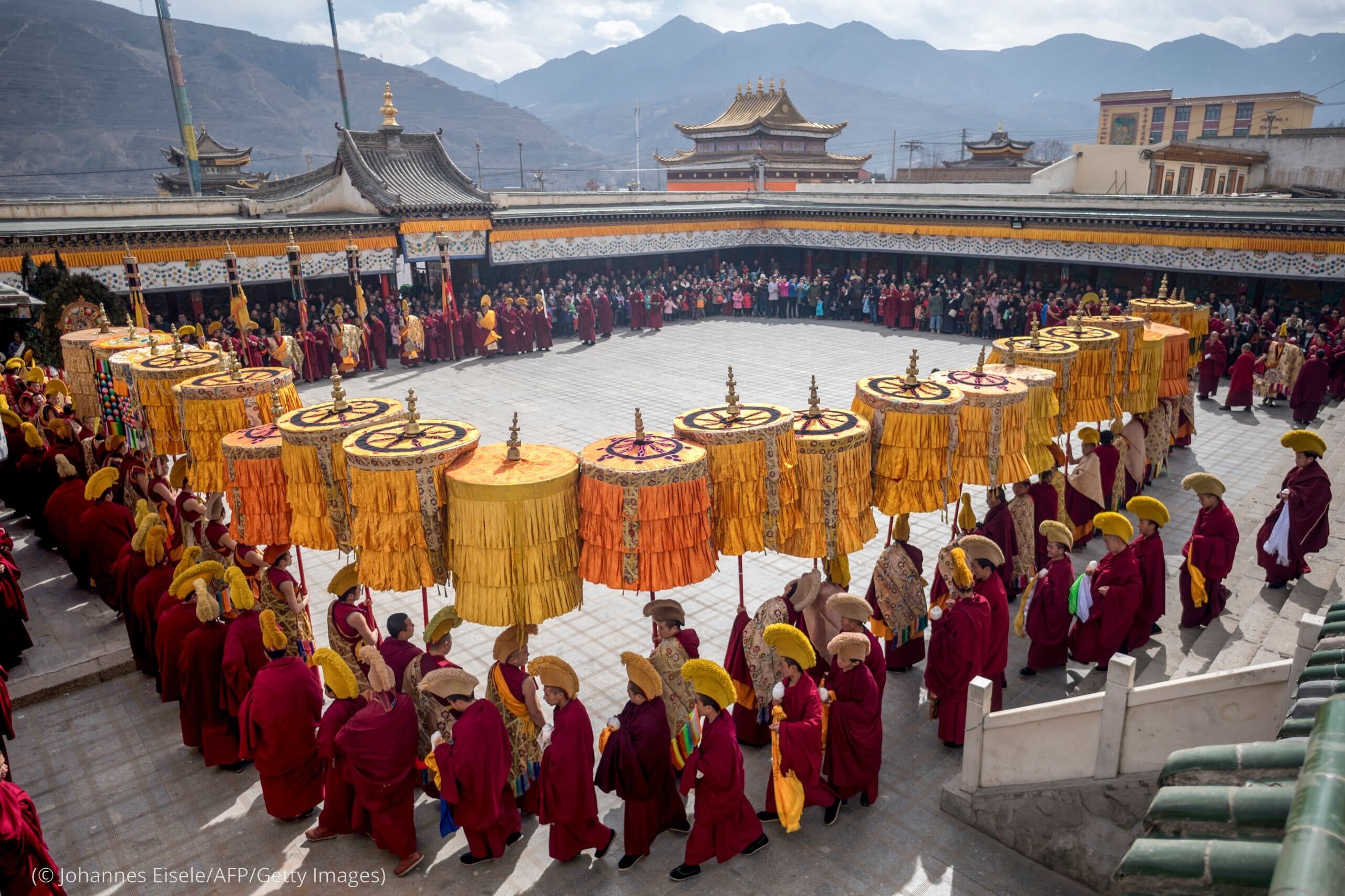 This picture taken on March 1, 2018 shows Tibetan Buddhist monks praying during a ceremony for Monlam, otherwise known as the Great Prayer Festival of Losar, the Tibetan New Year, at the Rongwo Monastery, in Tongren County, Huangnan Tibetan Autonomous Prefecture, on the Qinghai-Tibet plateau. Scores of monks and men heaved the enormous thangka -- an image of Buddha painted on silk, rolled up in a tight cylinder while in transit -- through the packed streets around Rongwo Monastery in China's northwestern province of Qinghai for a religious ritual wrapping up Losar, the Tibetan new year. [JOHANNES EISELE/AFP via Getty Images)]
