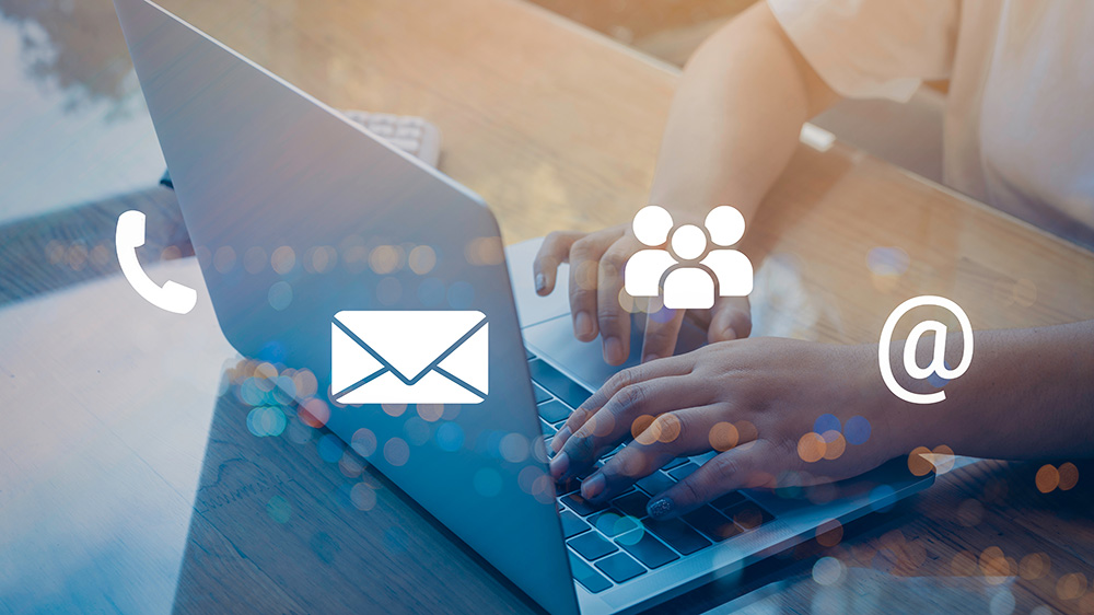 a person is using a laptop in background, with icons for a phone, envelope, people, and an @ symbol in white in foreground