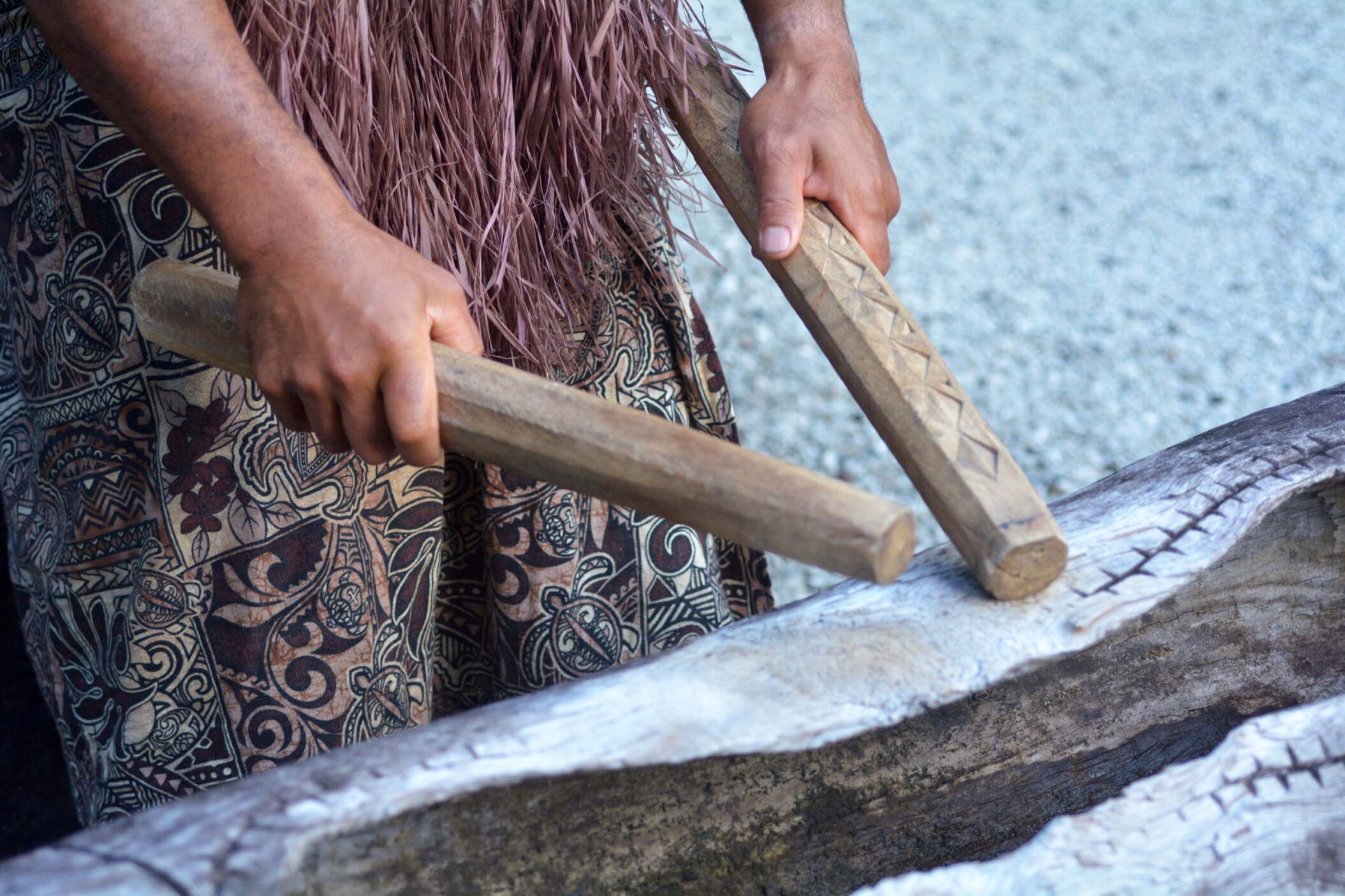 Cook Islander man plays on a large wooden log Pate drum instrument
